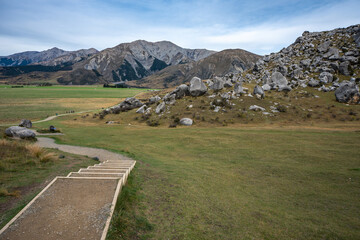 A wooden staircase and gravel walking trail lead visitors toward the limestone boulder field at Castle Hill (Kura Tawhiti), Canterbury, South Island, New Zealand. © ting_149