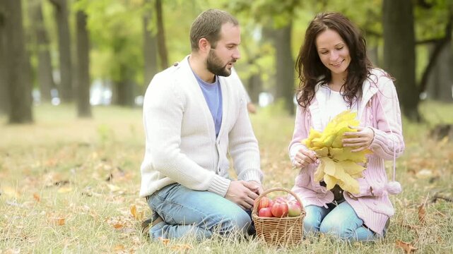 A happy young family with a child is having fun in the autumn park. Mother, father and daughter is hugging outdoors against blurred autumn leaves background. Slow motion