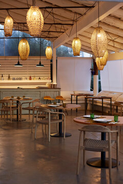 Luxury mediterranean restaurant interior with wooden furniture and decorative wicker pendant lamps