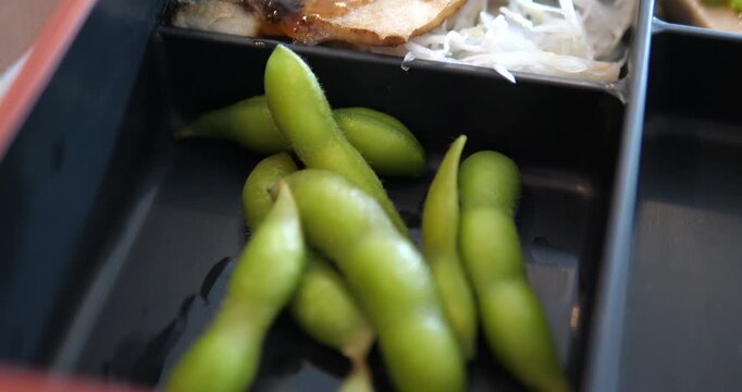 Close up of green edamame side dish in a bento box