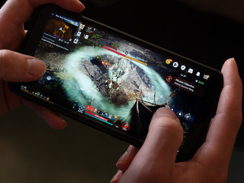Cork, Ireland, July 31, 2022. A smartphone in the hands of a white man. Playing mobile MMORPG Black Desert Mobile. A popular Korean mobile game on a smartphone screen, illustrative editorial.