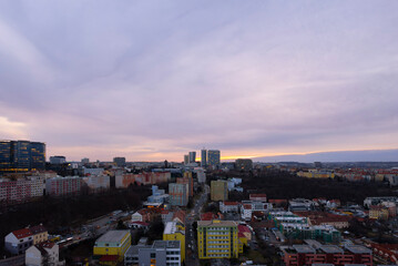 Obraz premium Aerial view of Prague's Michle district with V Tower on the horizon during a colorful winter sunset. Urban residential and business architecture captured from a drone without snow. 