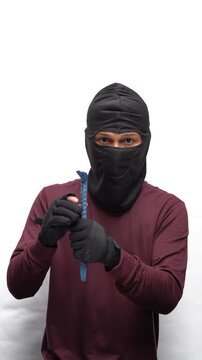 Thief wearing a black balaclava mask. Criminal in a dark shirt committing a crime. Dangerous intruder.