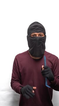 Masked thief holding a crowbar. Criminal wearing balaclava for burglary. Dangerous intruder in action.