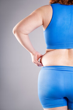 Rear view of woman pinching back fat and love handles. Concept of weight loss, liposuction and body contouring