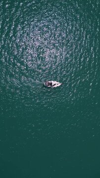 Top down aerial view of sailboat cruising in deep turquoise ocean water