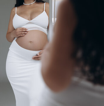 Pregnant woman reflection in mirror looking at bare belly