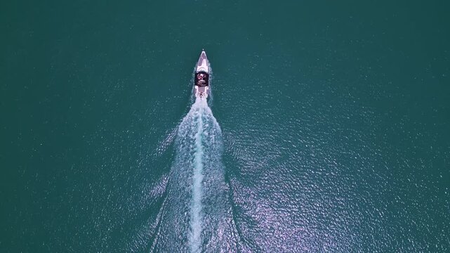Aerial top down view of a motorboat speeding through turquoise ocean water