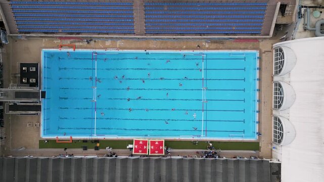 Aerial top down view of a water polo match in an outdoor swimming pool