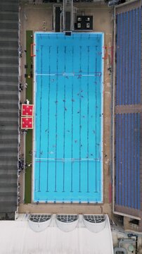 Aerial top down view of a water polo match in an outdoor swimming pool
