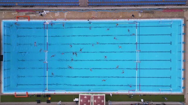 Aerial top down view of a water polo match in an outdoor swimming pool