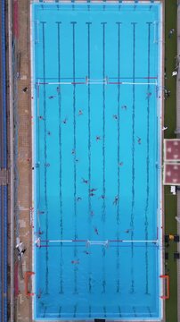 Aerial top down view of a water polo match in an outdoor swimming pool