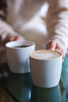 Vertical closeup image of a woman holding and serving two cups of hot coffee