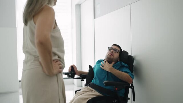 Scared man with a physical disability in an electric wheelchair experiencing respiratory distress or panic attack while talking to a caregiver