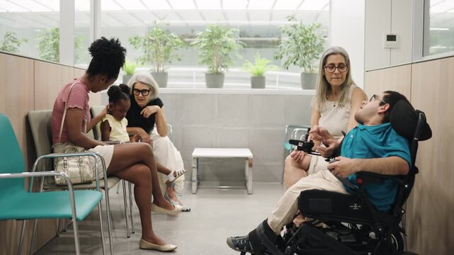 Inclusive scene with a diverse group of people in a hospital waiting room. A young man with a physical disability talking with others
