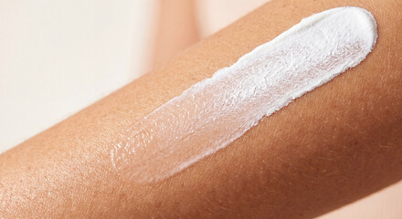 Fototapeta premium Close up view of a white moisturizing cosmetic face cream or sunscreen lotion smear swatch texture applied onto human skin. Dermatology and skincare product concept.