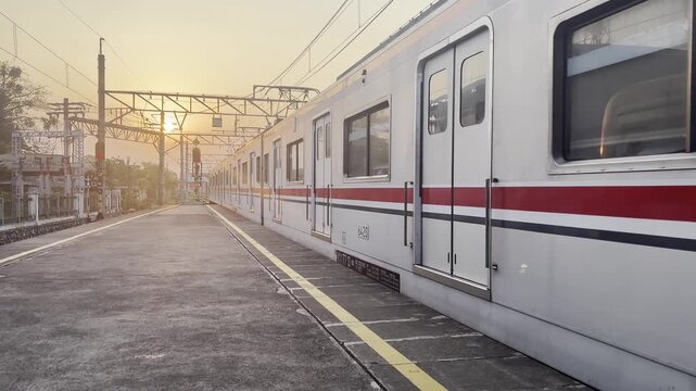 Video of a commuter train departing a railway station platform during sunset, illustrating modern public transportation and evening travel.