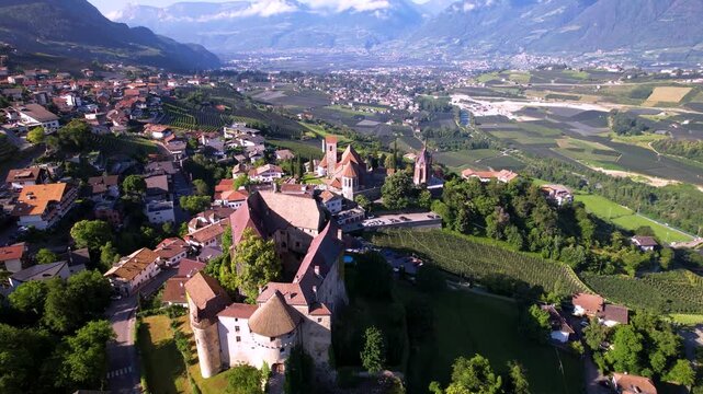 Schenna South Tyrol Italy 4K Drone. Aerial overflight from castle and church to green apple orchards and vineyards terraces. Merano valley mountain landscape background b-roll cinematic video asset