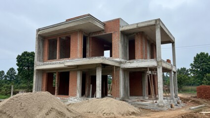 Fototapeta premium Contemporary two story residential building under construction with exposed concrete framework and unfinished exterior