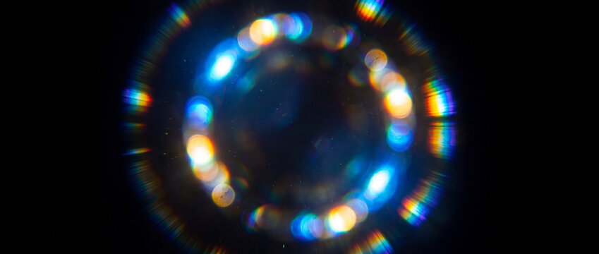 Cinematic circular lens flare overlay with colorful rainbow light leak bokeh and anamorphic ring reflections on a dark background for creative video editing and photo post-production
