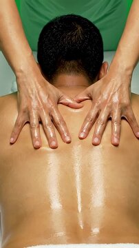 Relaxing Back Massage with Oil - Close-up of a therapist's hands applying oil and massaging a person's back, creating a sense of relaxation and well-being.