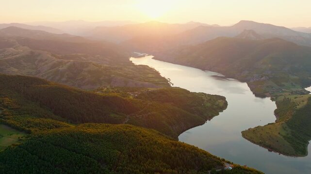 Kardzhali reservoir Arda river meander epic panoramic drone view sunset golden hour warm sun light green mountain ridges valley summer travel destination Bulgaria Rhodope landscape background.