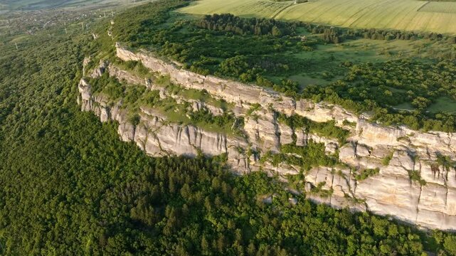 Madara Rider plateau steep rocky limestone cliffs aerial drone view green forest valley summer evening sunset light travel tourism landmark Shumen region Bulgaria landscape heritage background.
