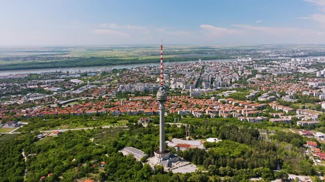 Ruse TV Tower red and white antenna spire epic aerial drone view Danube river city panorama green trees park summer daylight travel landmark Ruse region Bulgaria cityscape background.