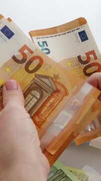 Close-up of female hand holding fifty euro bank notes vertical smartphone video orientation cash money distribution financial budget payment macro shot.