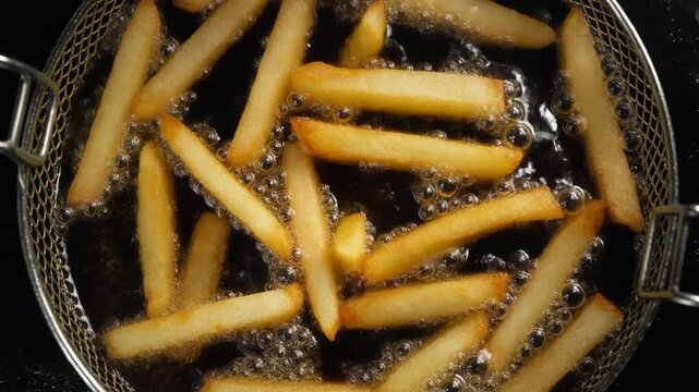 黄金色のフライドポテトが熱い油の中で勢いよく泡立ち香ばしい焼き色とカリッとした表面が輝く