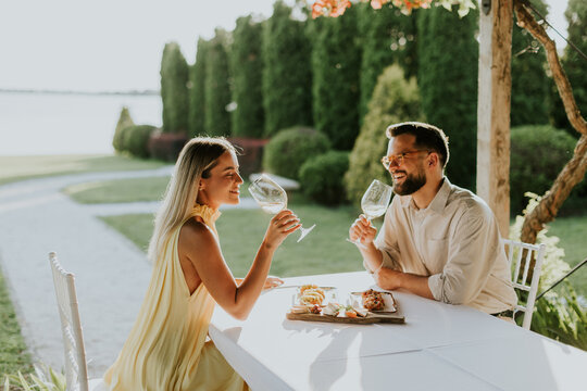 Couple enjoying a joyful dining experience by the lakeside at sunset