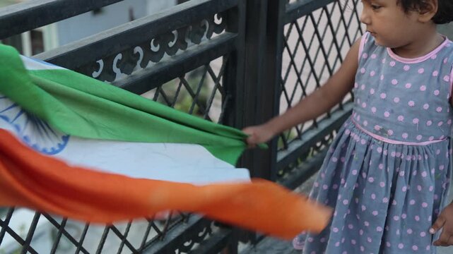 Indian toddler holding and waving the Indian national flag on a village rooftop, expressing childhood joy and patriotic spirit during the 15 August Independence Day celebration.