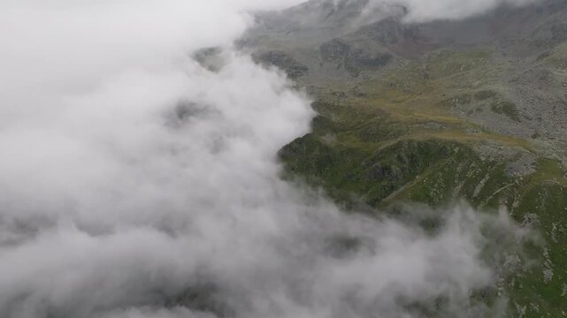 Aerial view of clouds above the Timmelsjoch mountain pass with breathtaking alpine peaks rocky ridges and valleys on the border of Austria and Italy in Europe