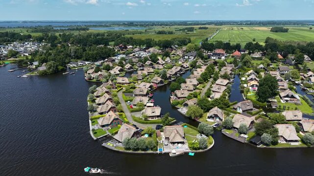 High altitude drone video with a 360-degree pan over a holiday park in the Netherlands. It shows a beautiful contrast between lush green nature and the vast blue water.