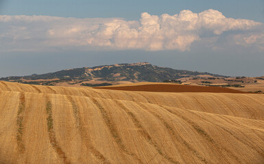 Obraz premium Harvested Fields with Medieval Hilltop Village and Storm Cloud, Tuscany Italy