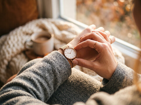 Woman checking her wristwatch by window.