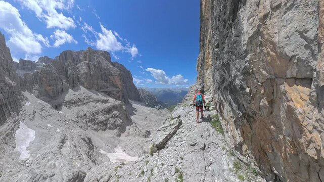 Two hikers traversing the spectacular ledge of Via Ferrata Bocchette Centrali in the Brenta Dolomites