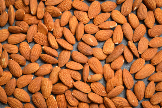 Raw organic almonds are scattered on a table. Delicious nuts form a large heap. Healthy vegan snack provides pure energy.