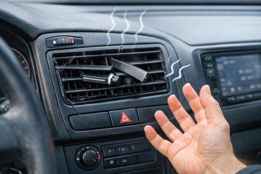 A person holds a cigarette while sitting in a car