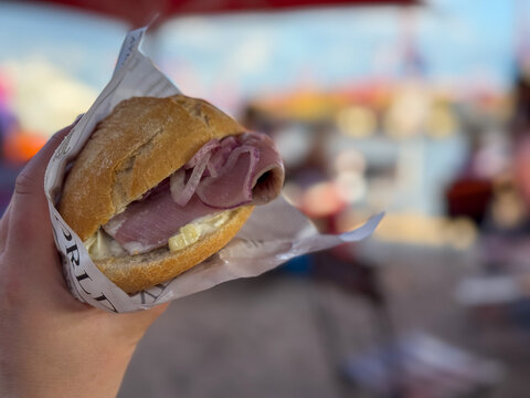 Traditional north german street food snack Fischbroetchen wheat bun with matjes fish fillet and onion in female hand close on Elbstrand beach