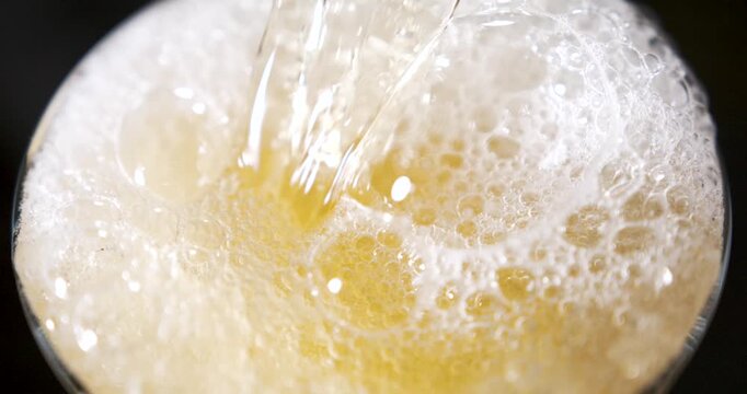 Pouring lager into a glass with foam forming in super slow motion