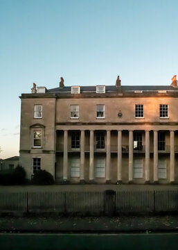 This image features a historic Georgian-style building in Bath, England, characterised by its elegant stone facade and a prominent ground-floor colonnade.