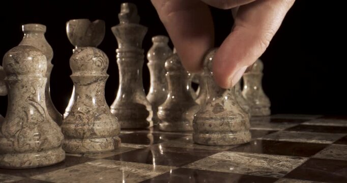 Hand moves chess piece on marble board in a quiet indoor space