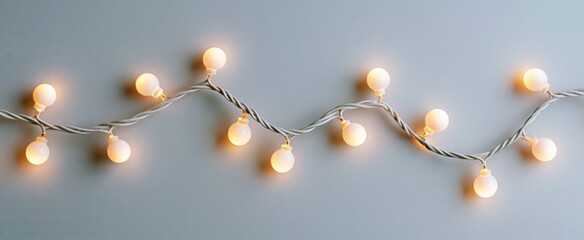 Fototapeta premium Cozy white Christmas garland lights shimmer gently on a simple winter backdrop for holiday cheer