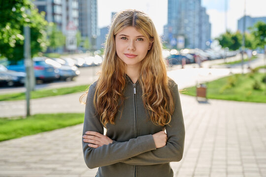 Portrait of beautiful confident young blonde woman looking at camera on modern city street
