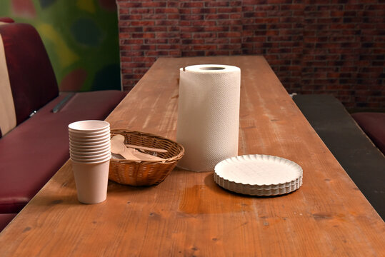 Disposable picnic supplies with paper plates and cups on wooden table