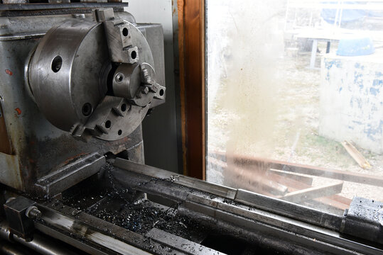 Industrial metal lathe chuck with metal shavings in a workshop