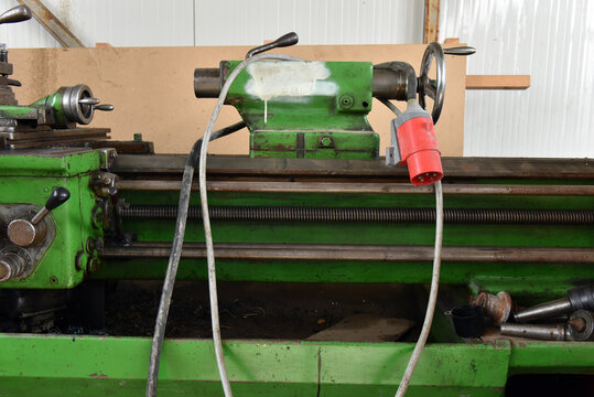 Green industrial metal lathe with three phase power plug in workshop