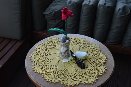 Handmade red crochet flower and grooming items on a yellow lace doily
