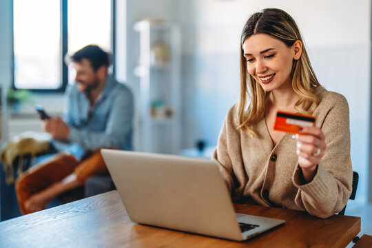 Young woman making an online payment with a credit card and laptop at home, cashless lifestyle